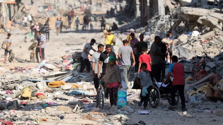 Palestinos caminham passando por prédios destruídos depois que os militares israelenses se retiraram do bairro de Shujaiya, a leste da Cidade de Gaza (AFP)