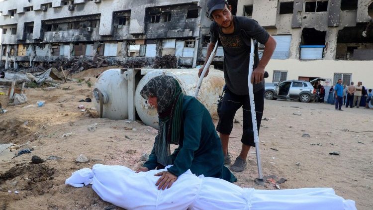 Sem poder chegar a um cemitério, palestinos enterram familiares em frente a hospital.